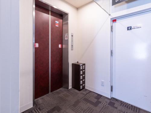 a elevator with a brown door in a room at Tabist Takamatsu Pearl Hotel in Takamatsu