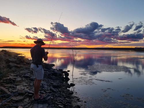 a man fishing on a lake at sunset at Teri-Lemveli Lodge in Beaufort West