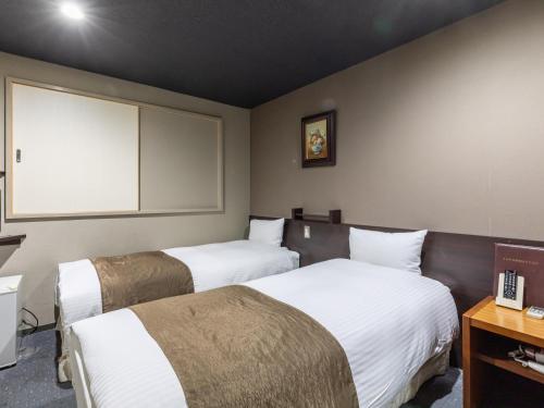 a hotel room with two beds and a television at Tabist Takamatsu Pearl Hotel in Takamatsu