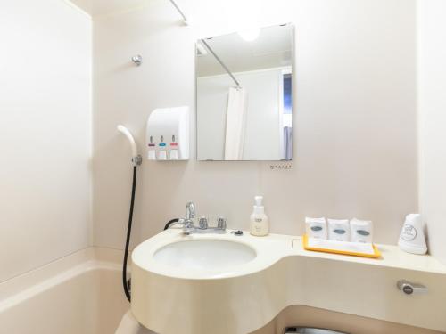 a white bathroom with a sink and a mirror at Tabist Takamatsu Pearl Hotel in Takamatsu