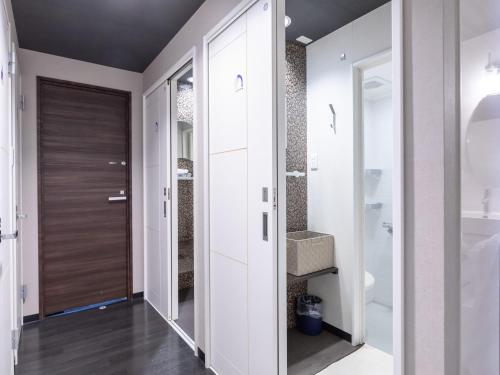 a bathroom with a walk in shower and a door at Tabist Takamatsu Pearl Hotel in Takamatsu