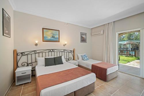 a bedroom with two beds and a balcony at Alados Otel in Turgut