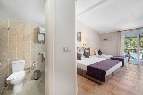 a bedroom with a bed and a toilet and a bathroom at Alados Otel in Turgut