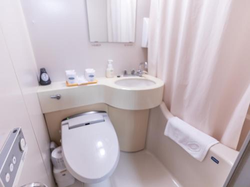 a white bathroom with a toilet and a sink at Tabist Takamatsu Pearl Hotel in Takamatsu