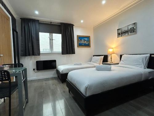 a hotel room with two beds and a television at VR Apartments in Glasgow