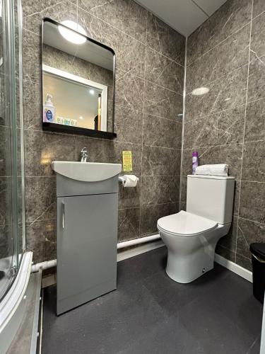 a bathroom with a toilet and a sink and a mirror at VR Apartments in Glasgow