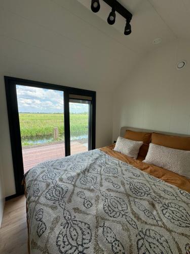 a bedroom with a large bed with a large window at TinyHouse Ochtendgloren in Haastrecht