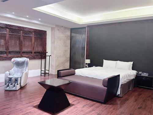 a bedroom with a bed and a couch and a table at Orient Luxury Villa Motel in Huwei