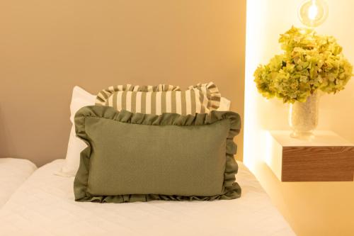 a pillow sitting on a bed with a vase of flowers at El Motín in Zamora