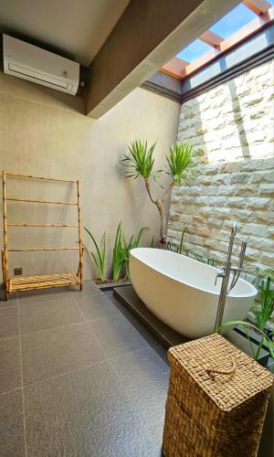 a bath tub in a bathroom with plants at HomeSix Bali in Uluwatu