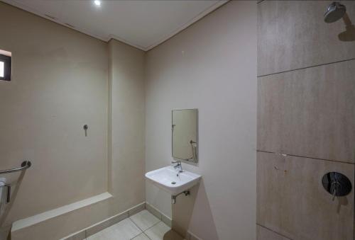 a white bathroom with a sink and a mirror at Postmasburg Inn in Postmasburg