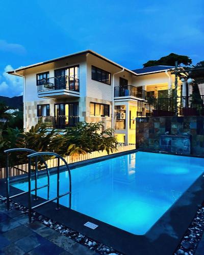 a large swimming pool in front of a house at Lodoicea Apartments in Bel Ombre