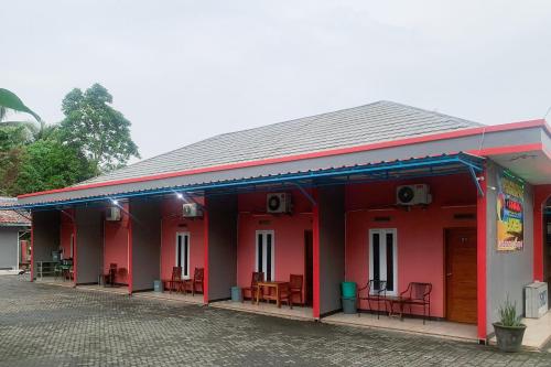 a red building with tables and chairs on it at Hana Losmen RedPartner in Babagan