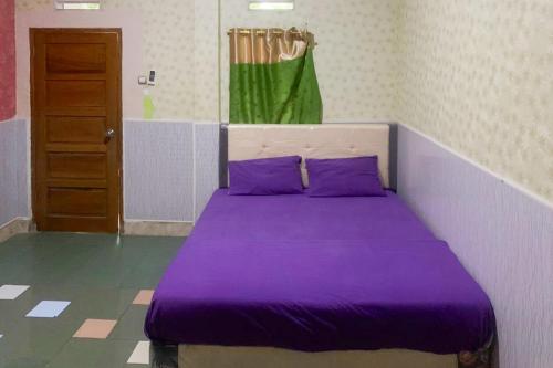 a purple bed with purple pillows in a room at Hana Losmen RedPartner in Babagan