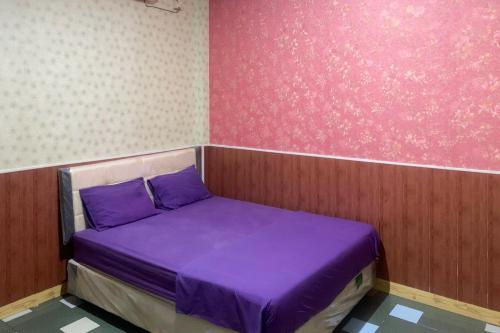 a small bed in a room with purple sheets at Hana Losmen RedPartner in Babagan