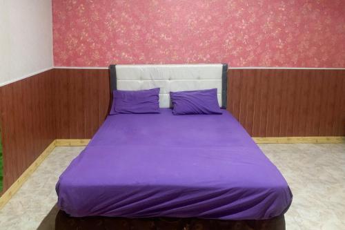 a purple bed with purple pillows in a bedroom at Hana Losmen RedPartner in Babagan