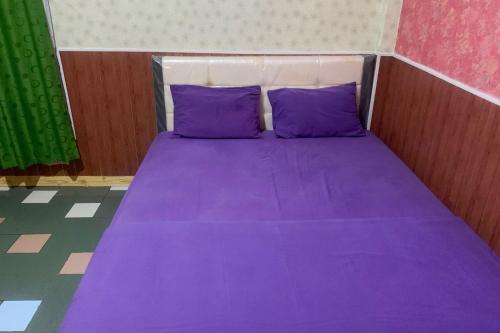 a purple bed with purple pillows in a room at Hana Losmen RedPartner in Babagan