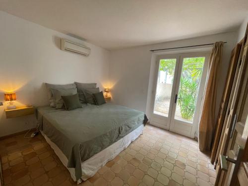 une chambre avec un lit et une porte coulissante en verre dans l'établissement Maison de Charme au Milieu des Vignes avec Jardin et Parking à Gassin, près de Saint-Tropez, à Gassin