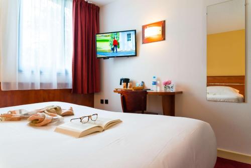 a bedroom with a bed with a book and glasses at Brit Hotel Rennes St Grégoire – Le Villeneuve in Saint-Grégoire