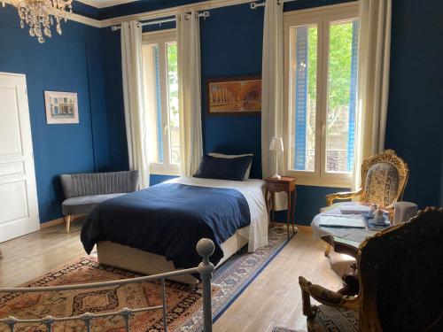- une chambre avec des murs bleus, un lit et une chaise dans l'établissement La Villa Celine, à Saint-Laurent-de-la-Cabrerisse
