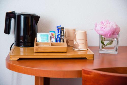 a table with a coffee pot and a vase with a flower at Brit Hotel Rennes St Grégoire – Le Villeneuve in Saint-Grégoire