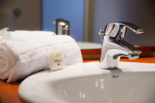 a bathroom sink with a towel on top of it at Brit Hotel Rennes St Grégoire – Le Villeneuve in Saint-Grégoire
