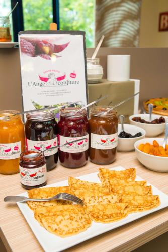 a table with a plate of food and jars of jam at Brit Hotel Rennes St Grégoire – Le Villeneuve in Saint-Grégoire