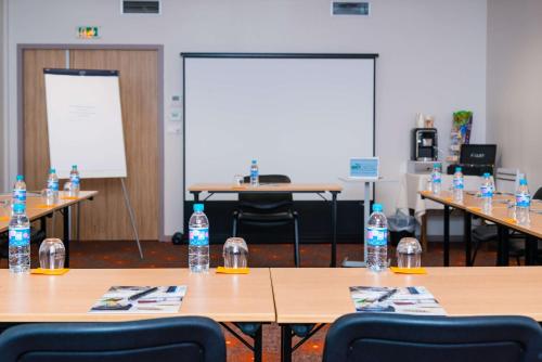 a classroom with bottles of water sitting on tables at Brit Hotel Rennes St Grégoire – Le Villeneuve in Saint-Grégoire