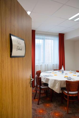 a conference room with a table and a sign on a wall at Brit Hotel Rennes St Grégoire – Le Villeneuve in Saint-Grégoire