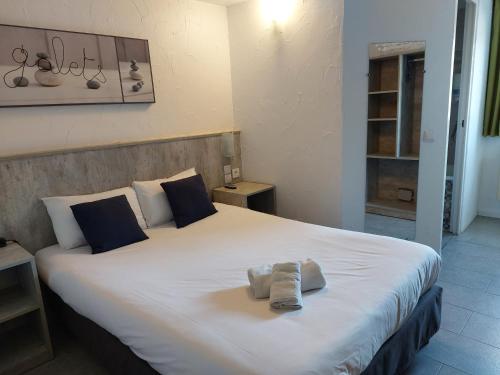 une chambre avec un grand lit blanc avec des serviettes dessus dans l'établissement Brit Hotel Bosquet Carcassonne Cité, à Carcassonne