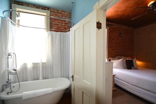 a bathroom with a bath tub and a bed and a window at Grand Highland Hotel in Prescott