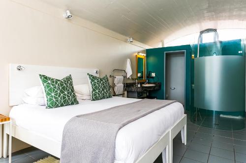 a bedroom with a large white bed with green accents at Speelhuis Collection in Langebaan