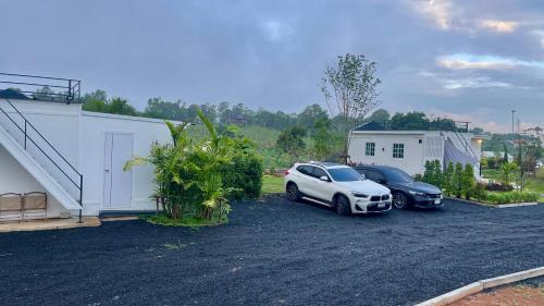 two cars parked in a parking lot next to a house at บ้านไร่ฟ้าสวย Nordic 02 in Ban Kom