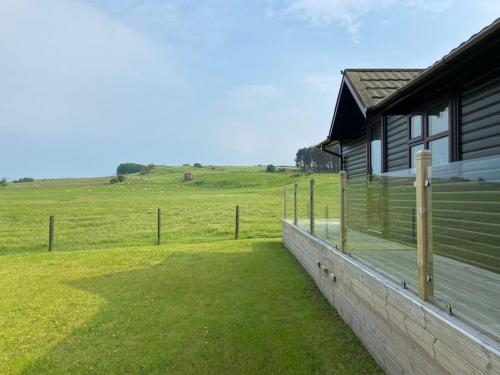 a house with a fence next to a field at Livingstones Lodge, Lake District in Plumbland