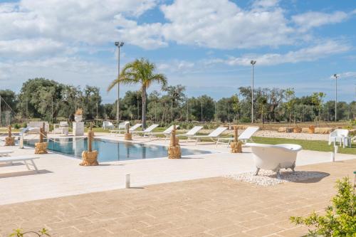 a pool with white benches and palm trees in a park at Dimora Tauro B&B in Fasano
