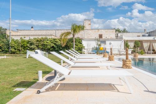 a row of white benches next to a pool at Dimora Tauro B&B in Fasano