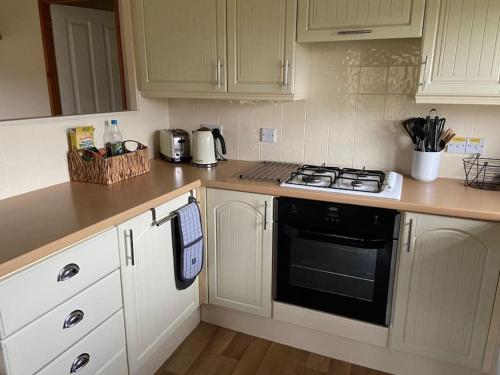 a kitchen with white cabinets and a black stove top oven at Livingstones Lodge, Lake District in Plumbland