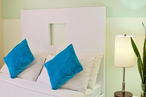a white bed with two blue pillows on it at Holiday Suites Business District - formerly Empire Suites Hotel in Puerto Princesa City