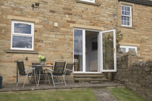 a patio with a table and chairs in front of a house at Penhill in Redmire