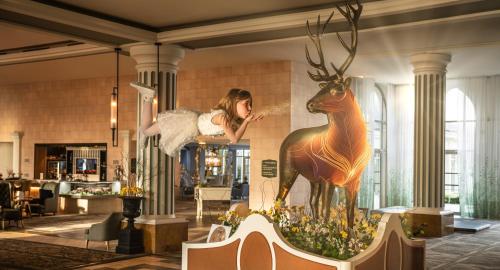 a woman is standing next to a statue of a deer at Dream Castle Hotel Marne La Vallee in Magny-le-Hongre