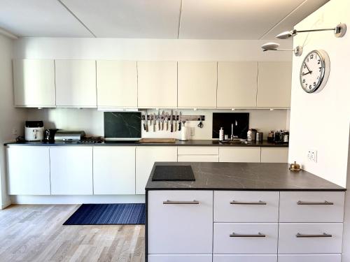 a kitchen with white cabinets and a clock on the wall at Spaniensgade 15A 1tv in Copenhagen