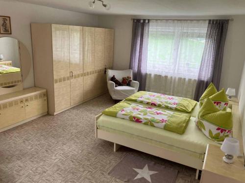 a bedroom with a bed and a chair and a mirror at Ferienwohnung Haus Elfriede in Neukirchen beim Heiligen Blut