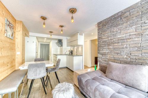 un salon avec un canapé et un mur en pierre dans l'établissement Homency - Résidence Les Mélèzes 14, à L'Alpe-d'Huez