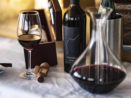 a glass of wine next to a bottle of wine at VitalZeit Hotel Weber in Bad Schönau
