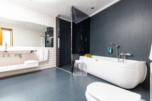 a bathroom with a tub and a toilet and a sink at Hotel Nou Romà in Denia