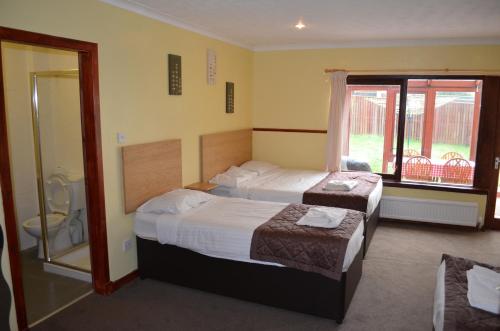 a hotel room with two beds and a bathroom at Boreland Lodge Hotel in Inverkeithing