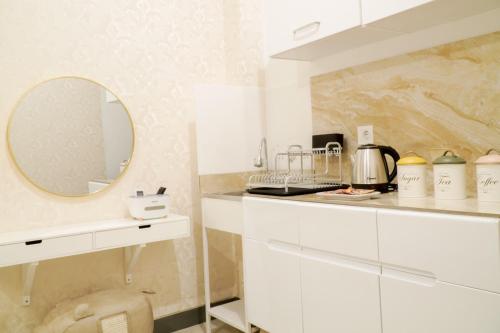 eine Küche mit weißen Schränken und einem Spiegel in der Unterkunft Let You inn in Surabaya