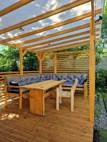 a wooden pergola with a bench and a table at Domek Pattie in Giżycko