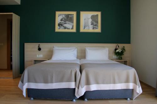 two beds in a bedroom with a green wall at Casa Calfelor Kolping Timișoara in Timişoara