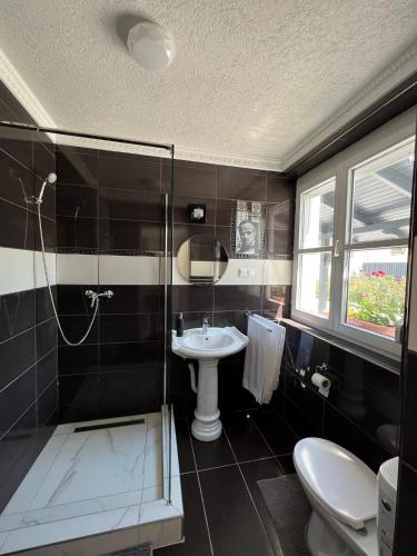 a bathroom with a sink and a shower and a toilet at Adél Apartman in Kisújszállás